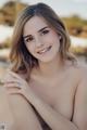 A beautiful young woman posing for a picture on the beach.