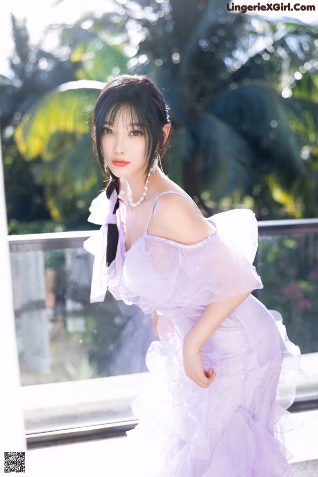 A woman in a purple dress posing for a picture.