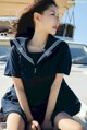 A woman in a sailor outfit sitting on a boat.