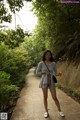 A woman in a gray dress is walking down a path.