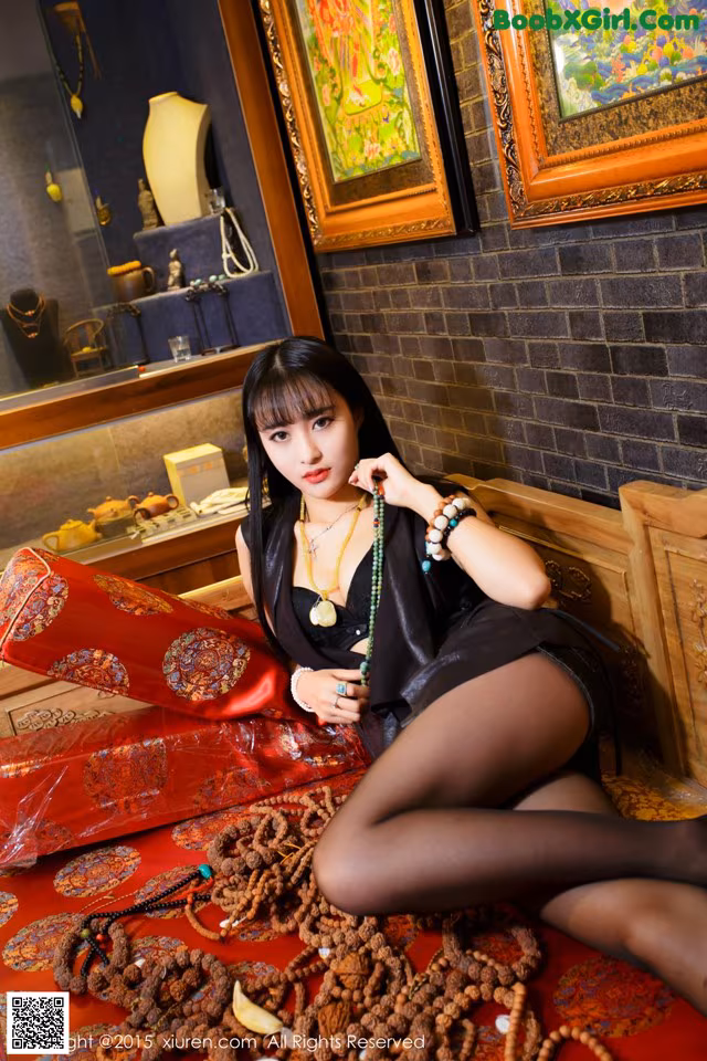 A woman sitting on a red rug in a room.