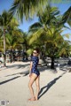 A woman in a polka dot swimsuit standing on a beach.