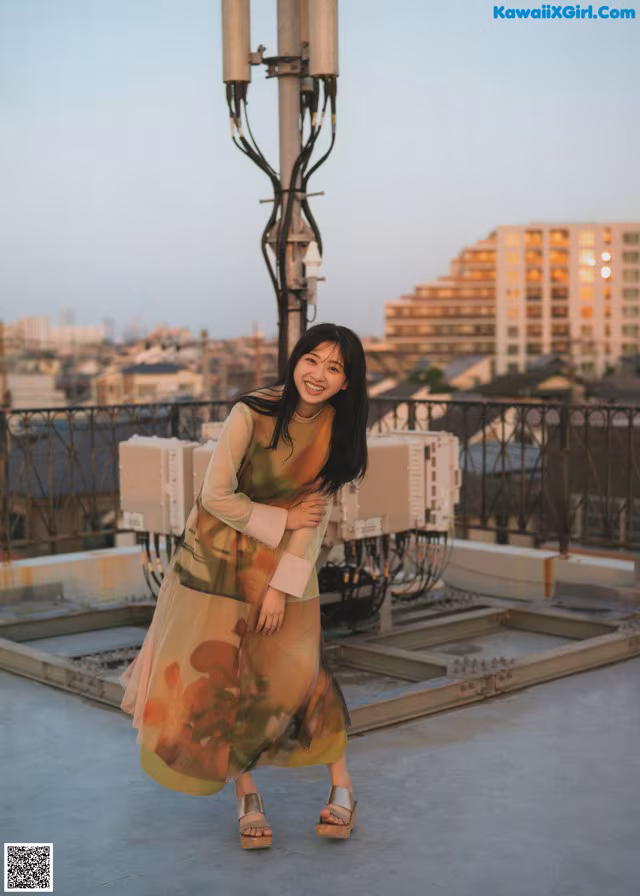 A woman standing on top of a building next to a street light.