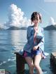 A woman in a blue kimono sitting on a dock by the water.