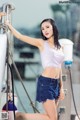 A woman in a white top and blue shorts posing on a boat.