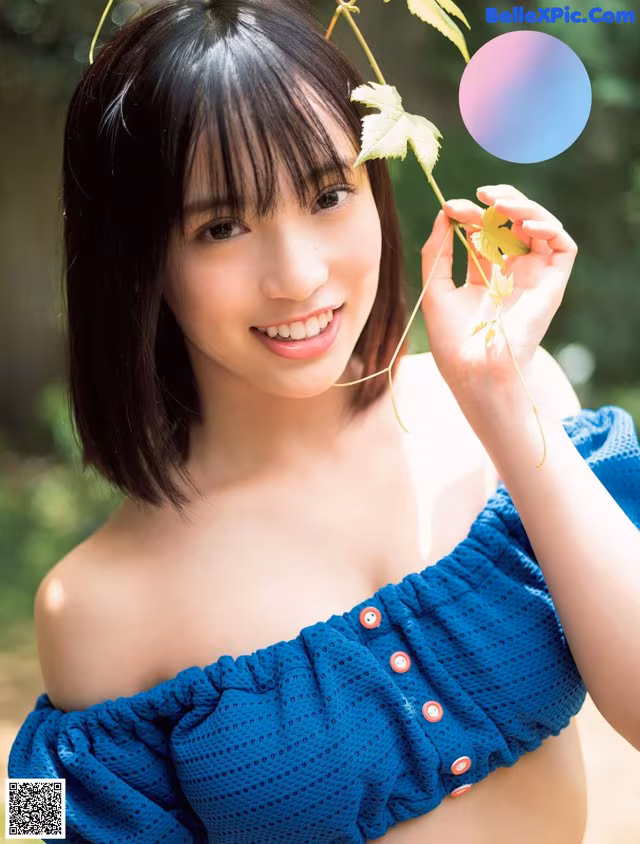A woman in a blue top holding a leaf.