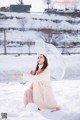 A woman sitting in the snow holding an umbrella.