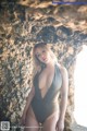 A woman in a gray swimsuit posing in a cave.