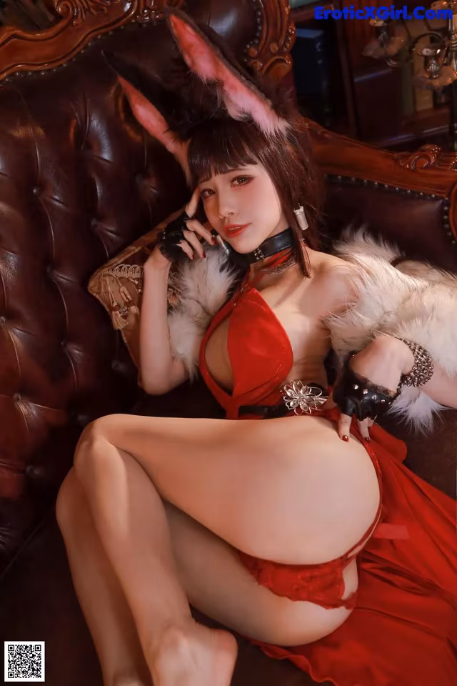 A woman in a red lingerie sitting on a brown couch.