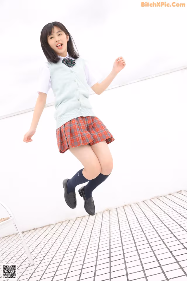 A young woman in a school uniform jumping in the air.