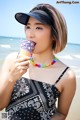 A woman eating an ice cream cone on the beach.