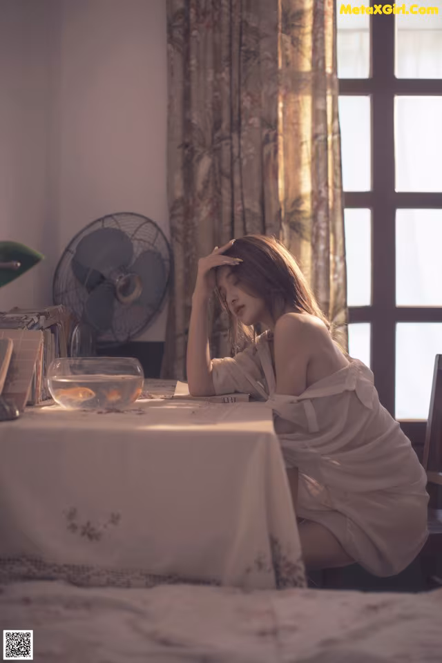 A woman sitting at a table in front of a window.
