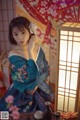 A woman in a blue kimono sitting on a table.