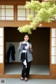 A woman standing in front of a door holding a flower.